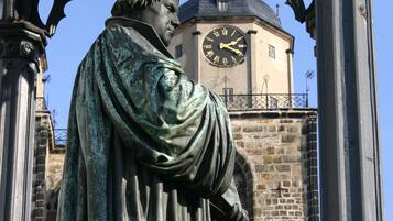 Una statua di una figura storica con una torre dell'orologio sullo sfondo.