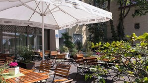 An outdoor café with wooden tables and chairs, a large white umbrella, and potted plants. - Best Western soibelmanns Lutherstadt Wittenberg (Lutherstadt Wittenberg)