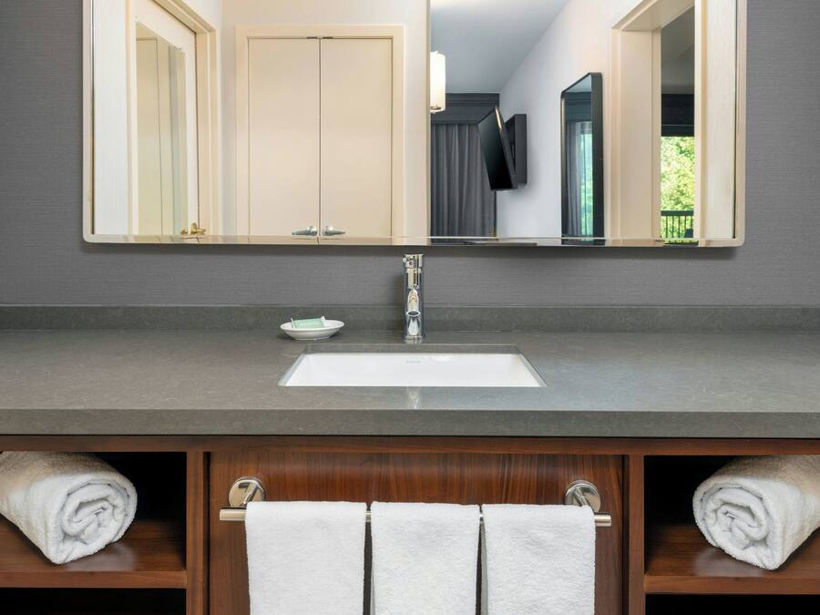 Un baño con un espejo grande, un lavabo y dos toalleros con toallas.