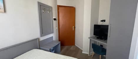 Une chambre d’hôtel comprenant un lit, un bureau avec une télévision, une armoire et une porte.