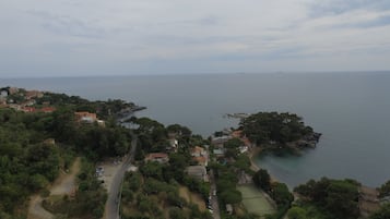An aerial view of a coastal town with a mix of residential buildings, a road, and a small island with dense vegetation.