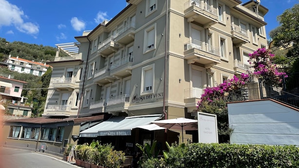 A hotel with multiple balconies, a sign for a snack bar, and outdoor seating with umbrellas. - Hotel Rosa dei Venti (Lerici)