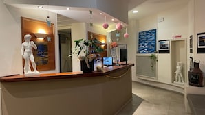 A reception desk with a white statue, a computer, and a potted plant. - Hotel Rosa dei Venti (Lerici)