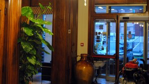 Un intérieur en bois agrémenté d’une grande plante, d’un lustre et d’une vue sur l’extérieur, visible à travers une porte vitrée.