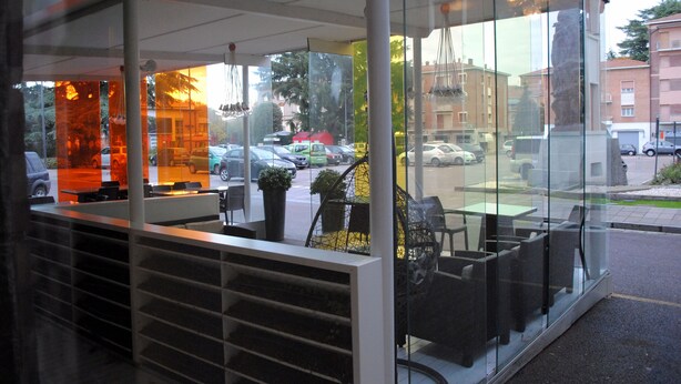 Un restaurant moderne doté d’une véranda en verre, d’une terrasse et offrant une vue sur la rue.