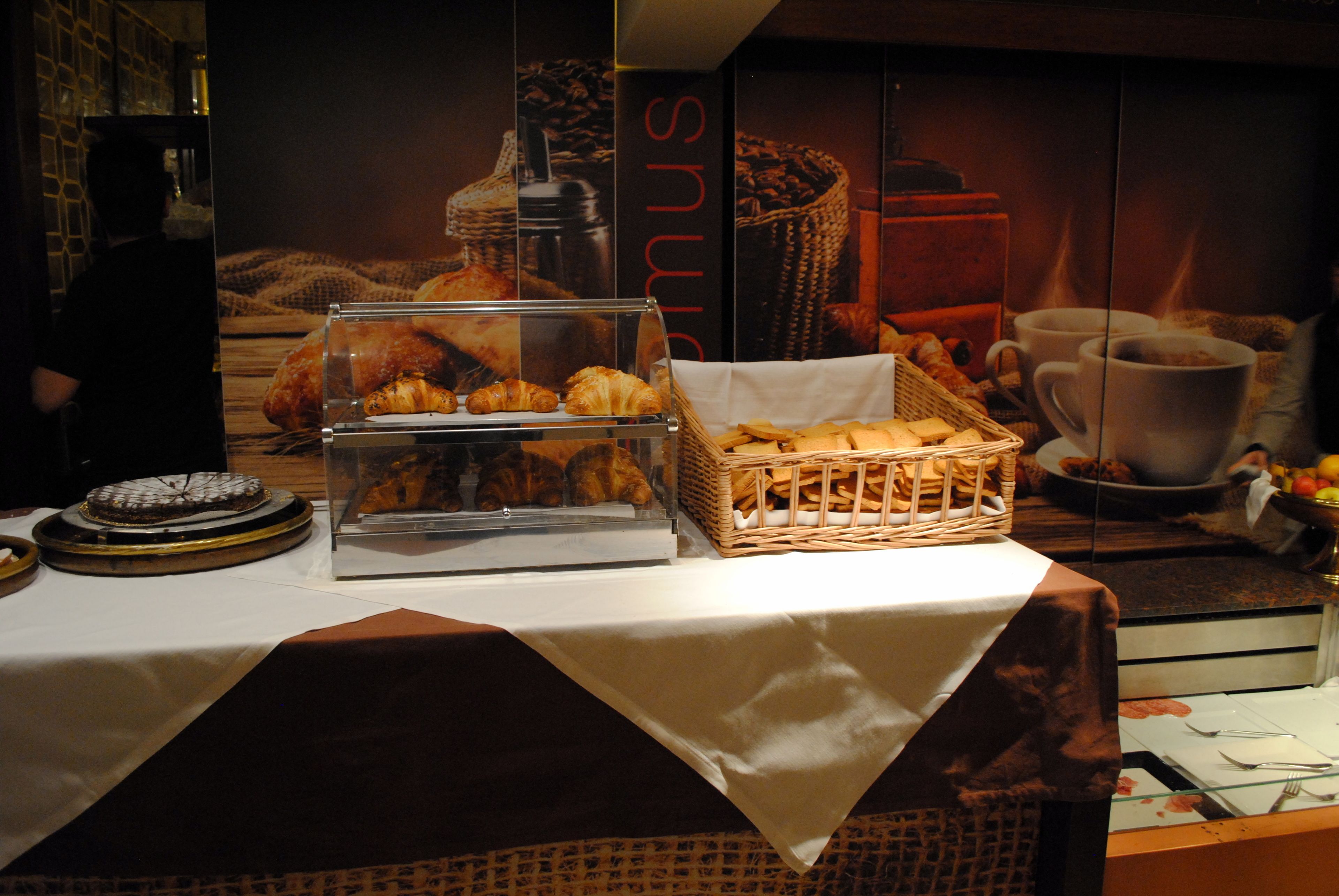 A breakfast buffet with pastries, a coffee machine, and a basket of bread.