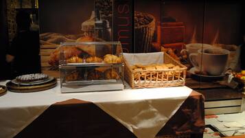 A breakfast buffet with pastries, a coffee machine, and a basket of bread.