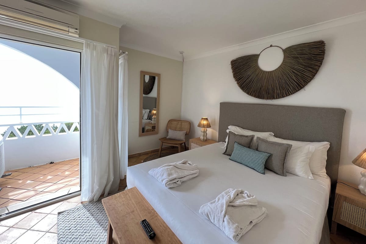 A hotel room with a bed, a nightstand, a chair, a lamp, and a large mirror.