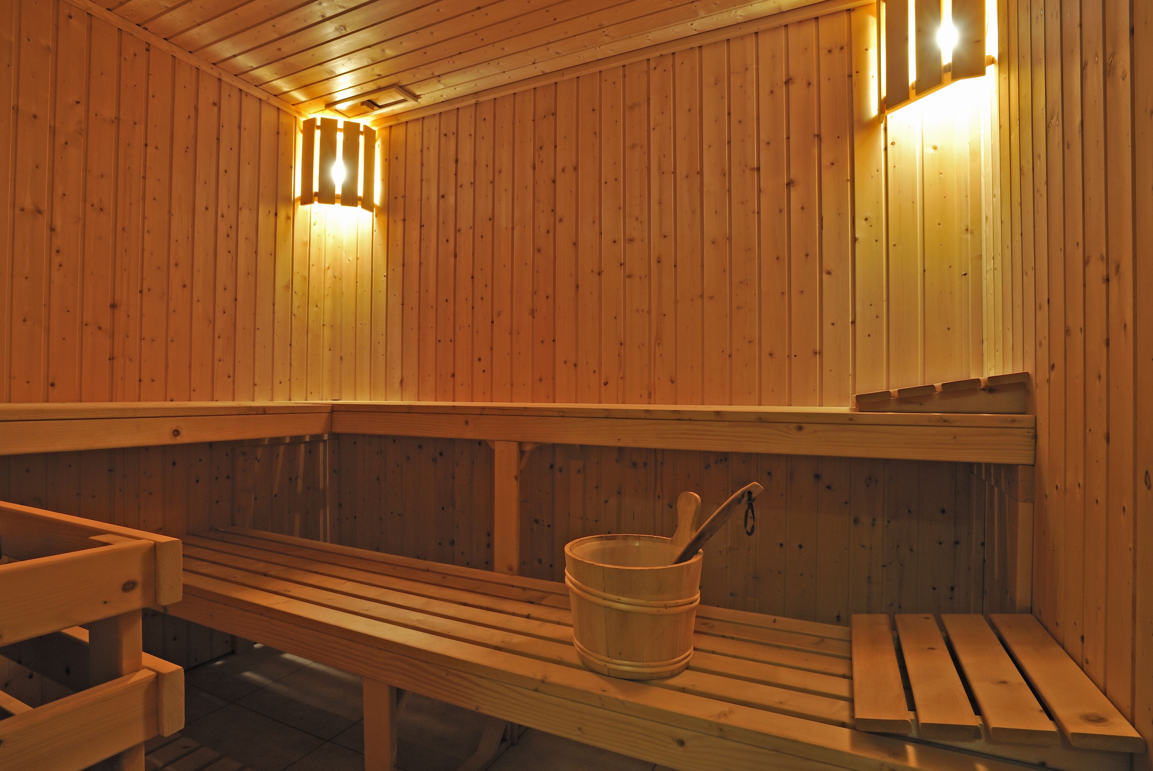 A wooden sauna with benches and a bucket with a ladle.