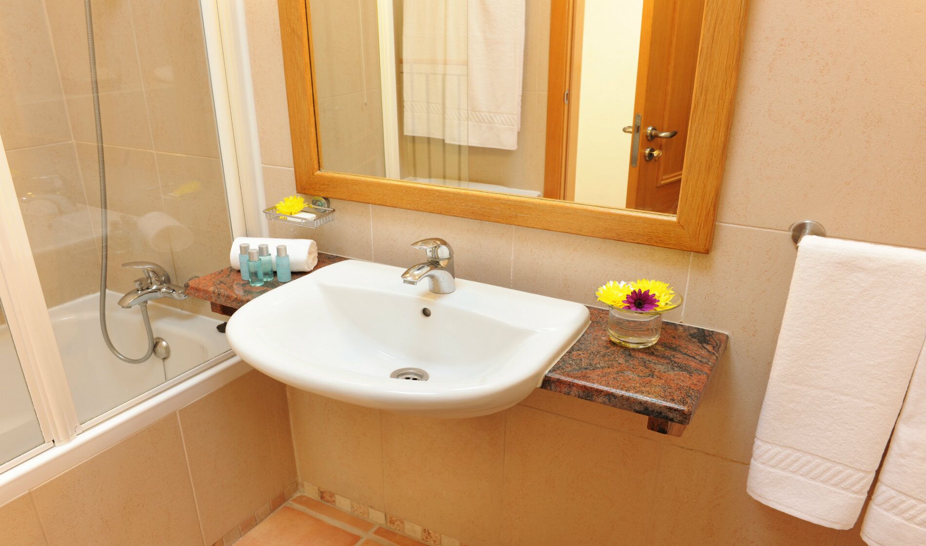 A bathroom with a white sink, a shower, and a mirror above the sink.