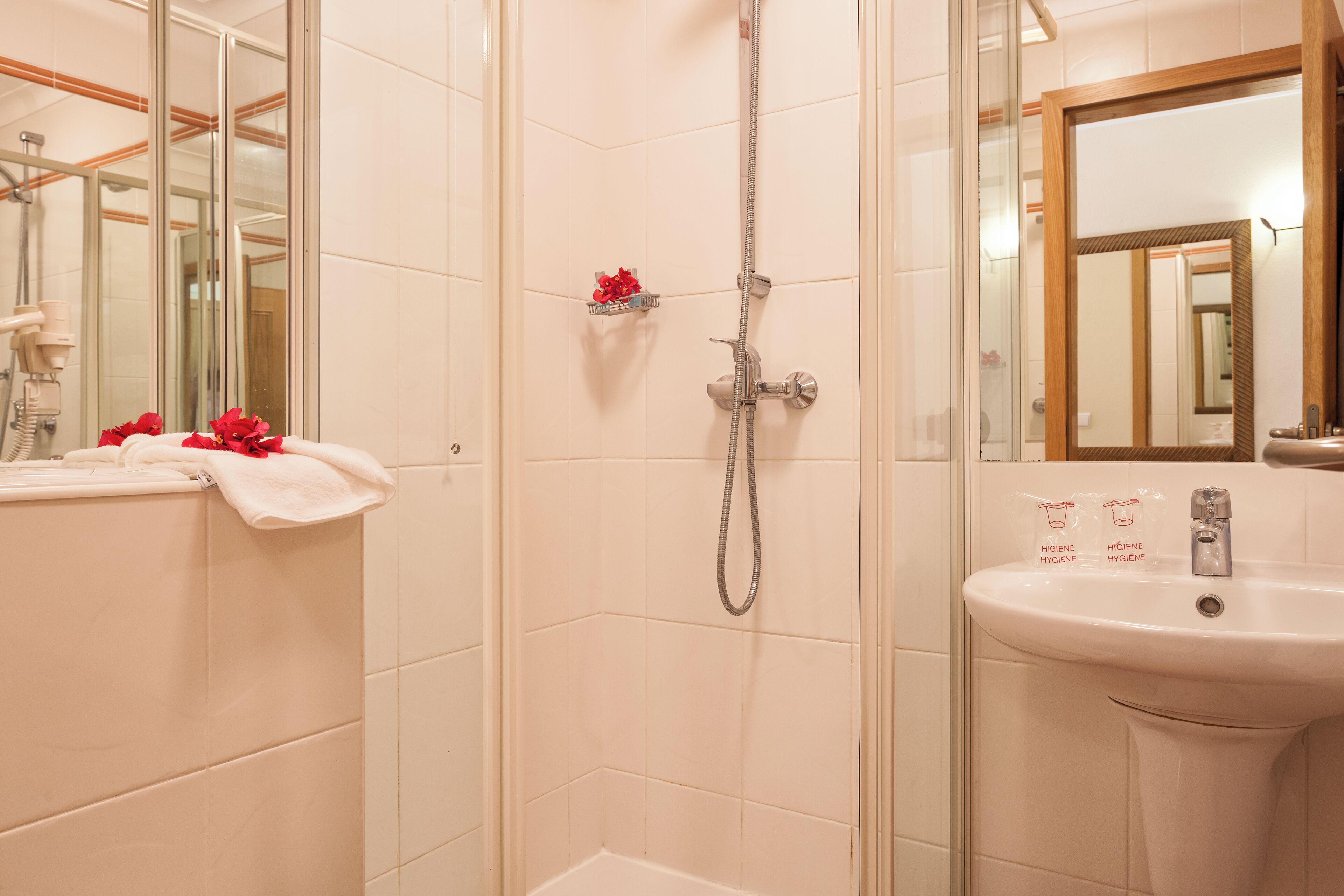 Un baño con ducha, lavamanos y espejo.