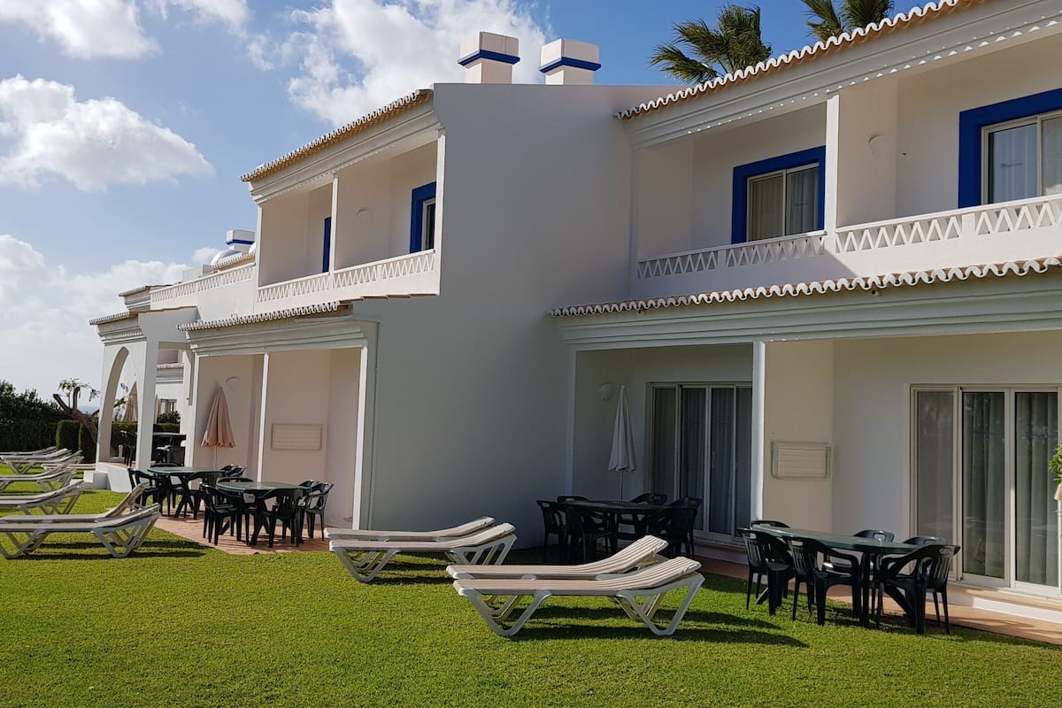 A two-story building with a balcony, outdoor seating, and a well-maintained lawn.