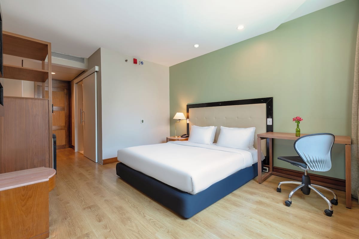 Ein Hotelzimmer mit Bett, Schreibtisch, Stuhl und Kleiderschrank.