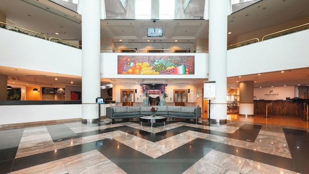 Un hall d’entrée spacieux avec un sol à carreaux, un espace salon central et une grande fresque murale à l’étage supérieur.