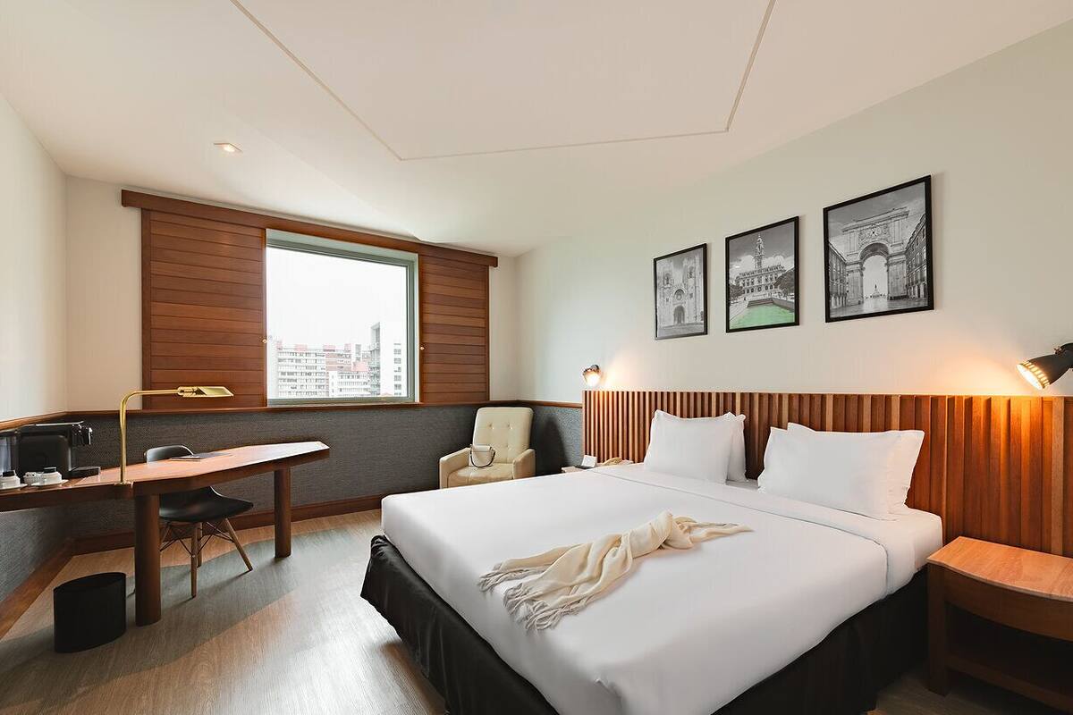 Ein Hotelzimmer mit Bett, Schreibtisch, Stuhl und einem Fenster mit Blick.