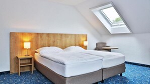 Ein Schlafzimmer mit einem Holz-Kopfteil, zwei Nachttischlampen, einem kleinen Tisch und einem Oberlicht.