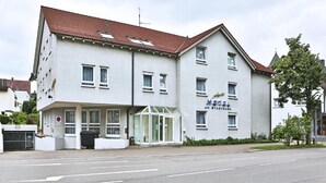 Ein zweistöckiges Hotel mit rotem Ziegeldach, einem Glastür-Eingang und einem Schild, das es als Hotel kennzeichnet.