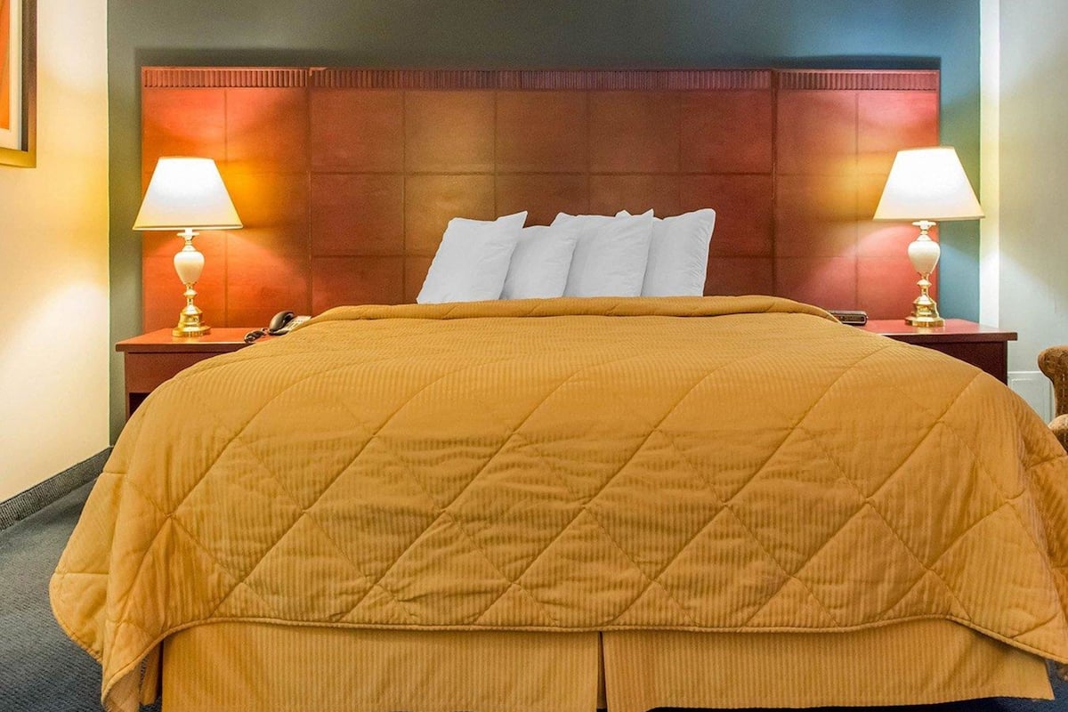 A hotel room with a large bed, two bedside tables with lamps, and a wooden headboard.