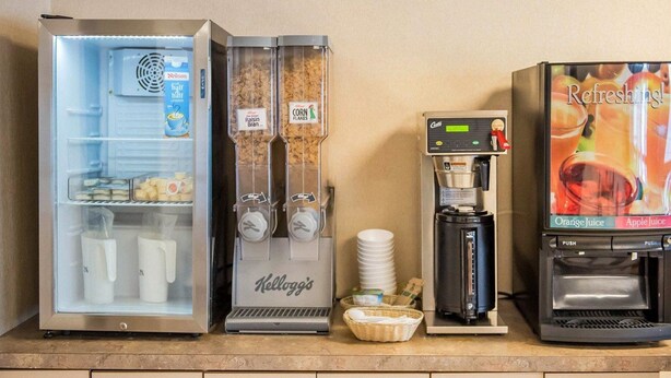 A self-service beverage station with a refrigerator, a coffee machine, and a juice dispenser. - Econo Lodge (Smiths Falls)