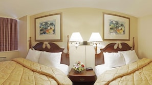 A hotel room with two beds, each with a wooden headboard, white bedding, and a nightstand with a lamp and a vase of flowers. - Econo Lodge Smiths Falls (Smiths Falls)