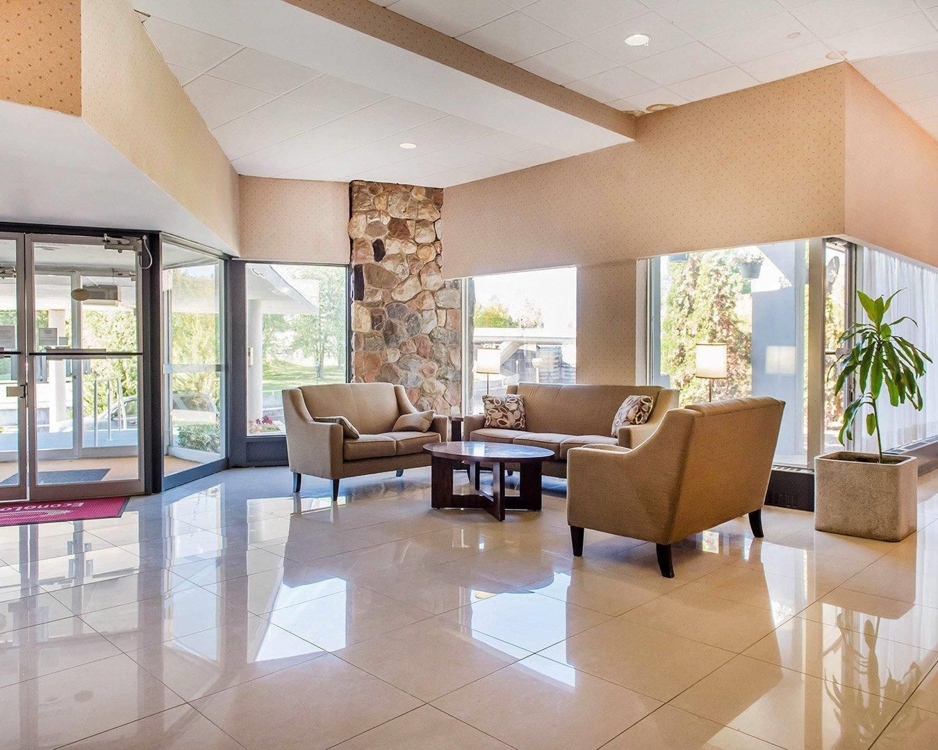 A lobby with a stone accent wall, a seating area with sofas and a coffee table, and large windows offering views.