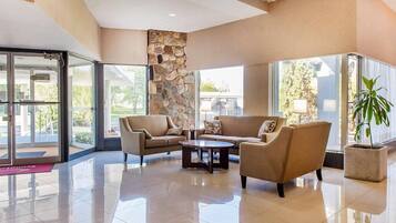 A lobby with a stone accent wall, a seating area with sofas and a coffee table, and large windows offering views.