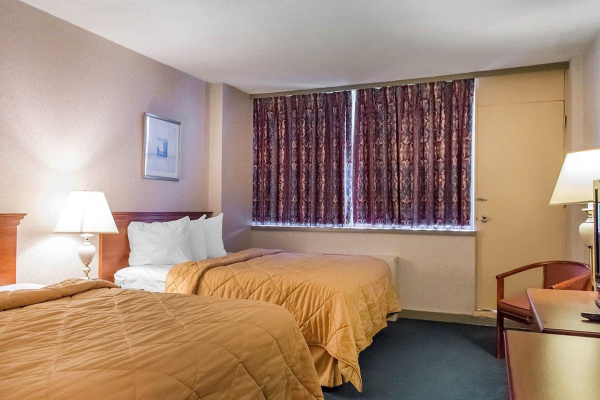 A hotel room with two beds, a desk, and a chair.