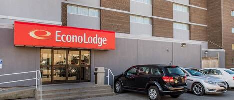 Un hotel llamado EconoLodge con un toldo rojo, un estacionamiento con varios coches y una fachada de ladrillo.