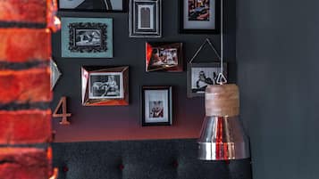 A dining area with a tufted headboard, framed pictures on the wall, and a hanging pendant light.