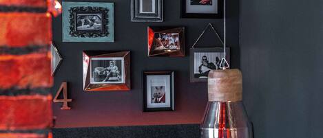 A dining area with a tufted headboard, framed pictures on the wall, and a hanging pendant light.