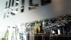 A hotel interior with a reception desk, a sign reading "PENTA HOTEL," and a wooden floor with "PENTA HOTEL" branding. - pentahotel Paris Charles de Gaulle Airport (Roissy-en-France)