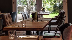 A dining area with a wooden table and chairs, a bottle, and glasses. - pentahotel Paris Charles de Gaulle Airport (Roissy-en-France)