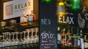 A bar area with a sign reading 'RELAX FOOD, DRINKS & YOU', glassware, and various liquor bottles. - Mercure Hotel Berlin City (Berlin)