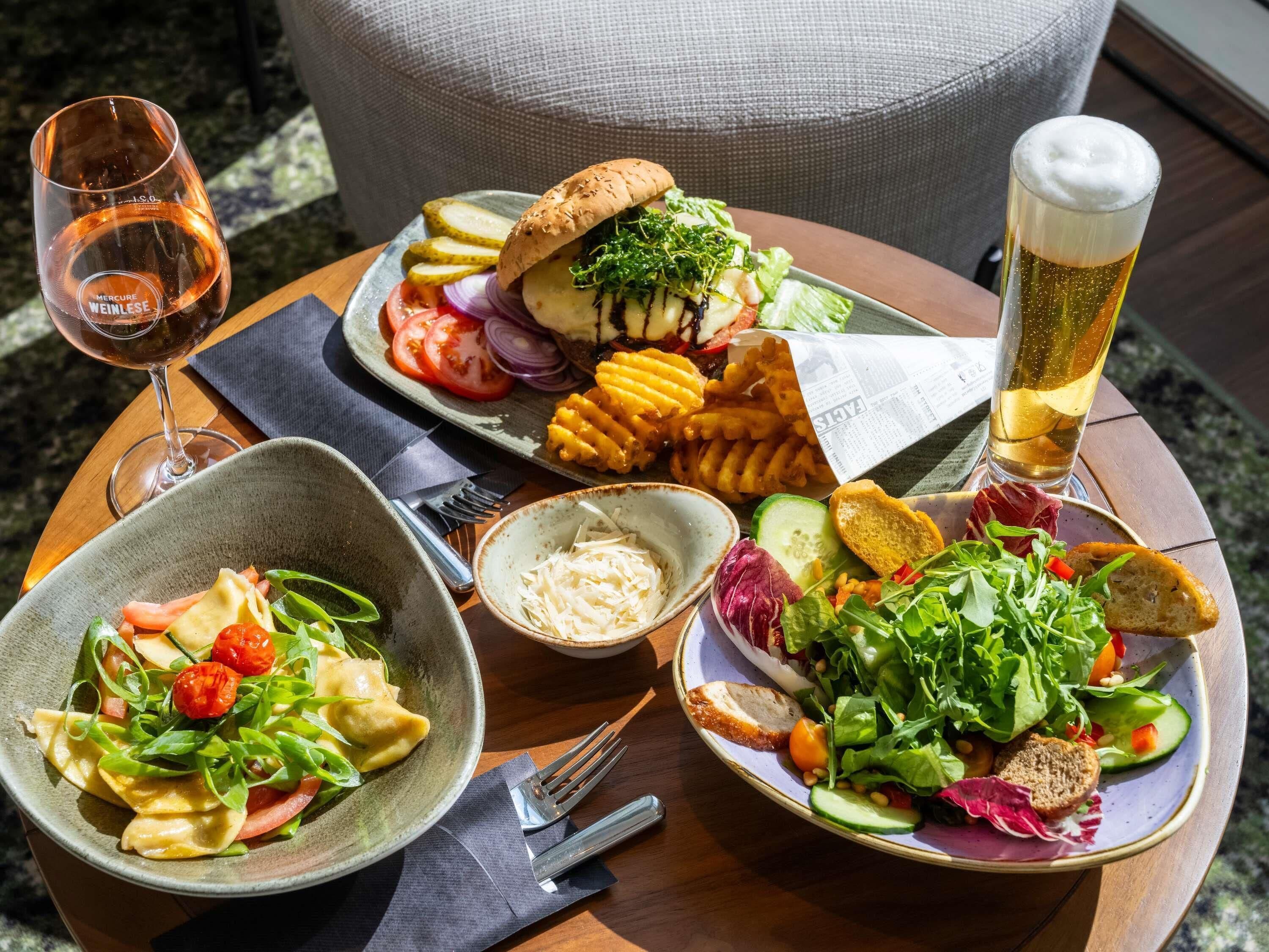 A table with various dishes, a glass of wine, and a glass of beer.