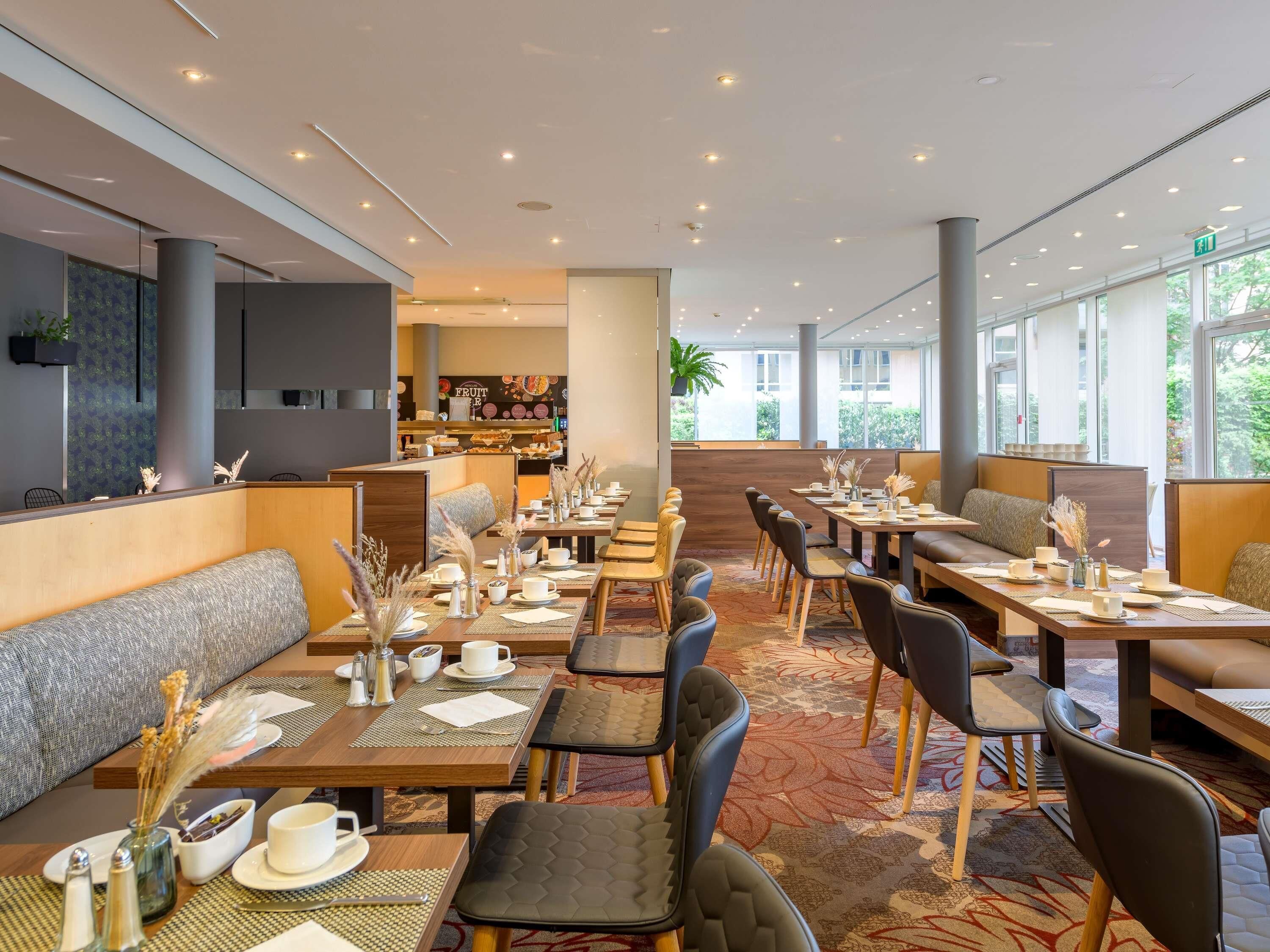 Un restaurante moderno con techos altos, iluminación empotrada y una zona de bar central.