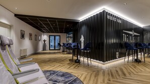 A modern reception area with a black reception desk, blue chairs, and a wooden floor. - Mercure Neu-Isenburg (Neu-Isenburg)
