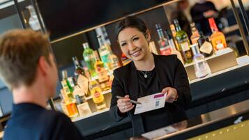 A bar area with a counter and a variety of liquor bottles in the background.