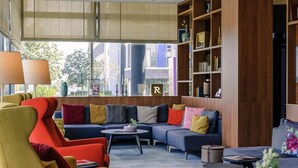 A modern living room with a sofa, armchairs, a coffee table, and a bookshelf.
