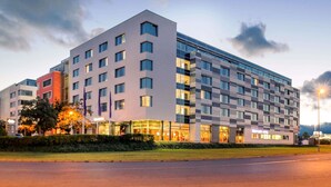 A modern hotel with multiple floors, large windows, and a well-lit entrance.