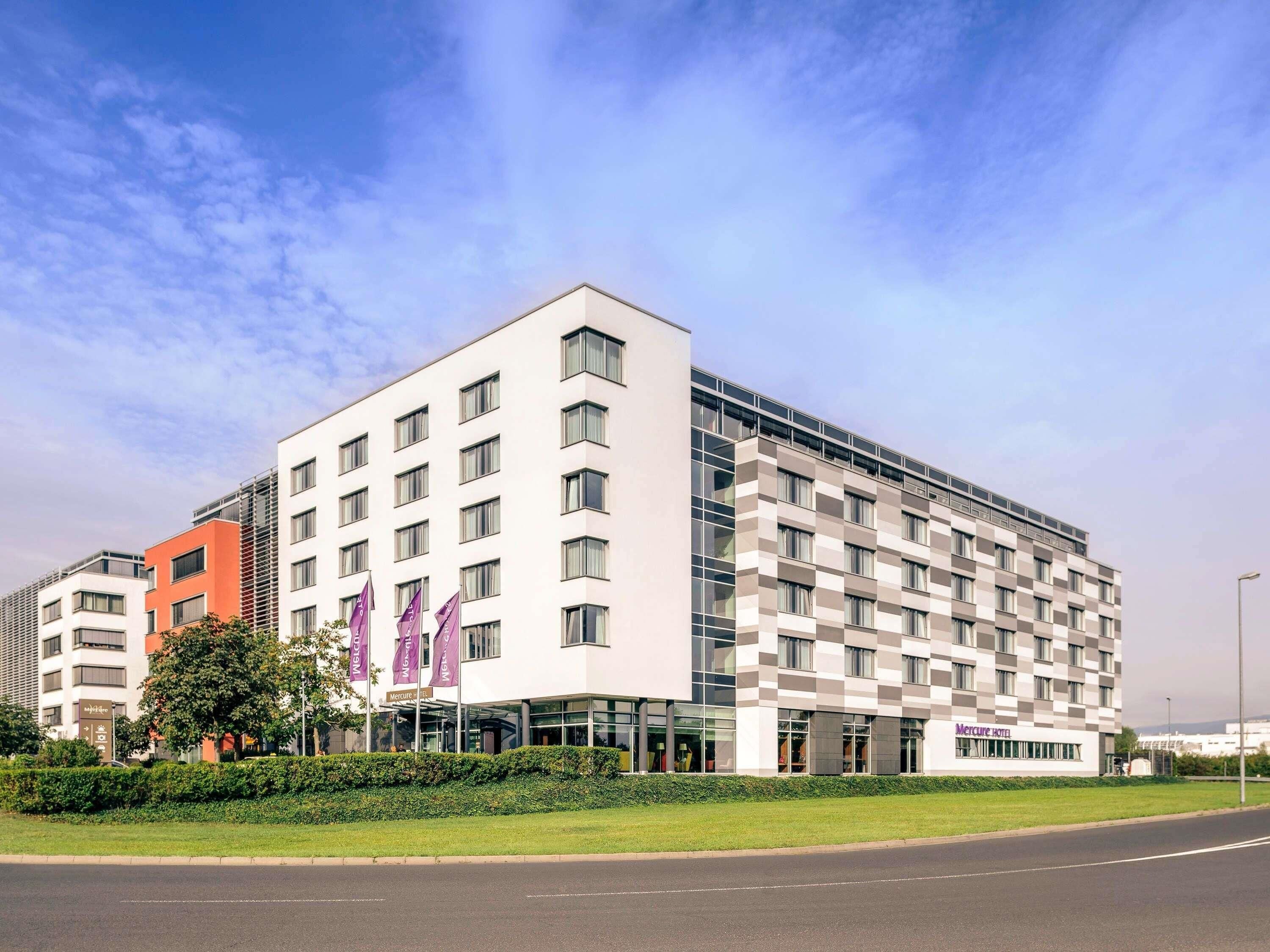 Un moderno edificio de hotel con fachada a cuadros, varios pisos y una entrada destacada con puertas de vidrio.
