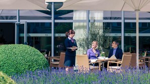 Un espace extérieur aménagé avec des tables et des chaises, un serveur et un client.