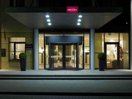 Entrada de hotel com porta giratória, placa com 'Mercure' e o nome 'ACCOR' visível.