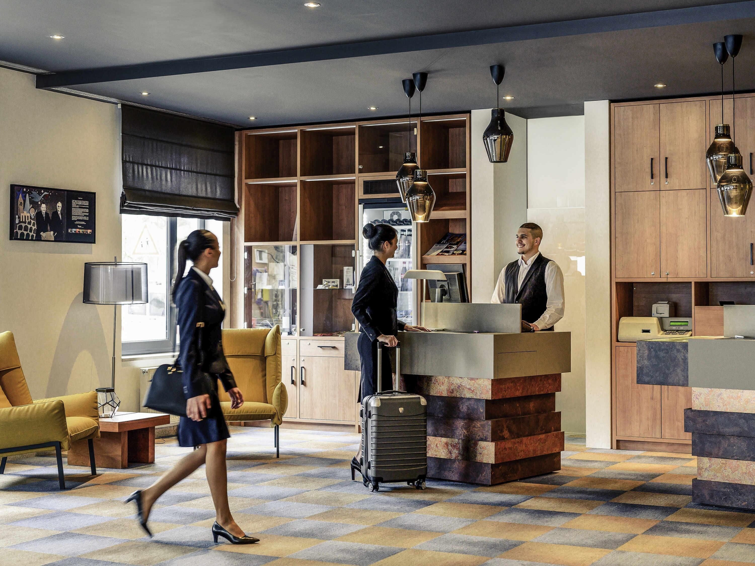 A hotel lobby with a reception desk, seating area, and a large window.