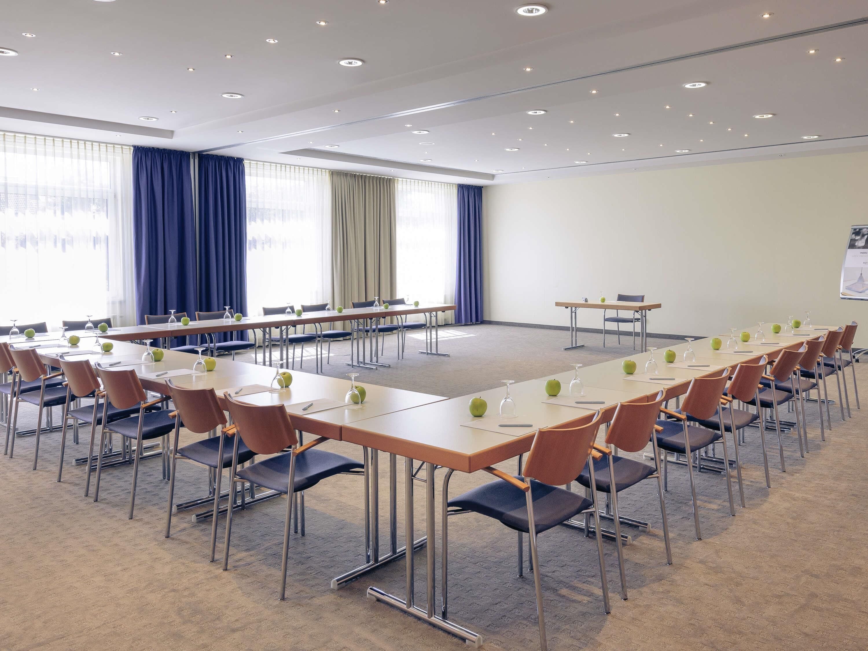 A conference room with multiple tables, chairs, and a carpeted floor.
