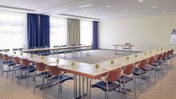 A conference room with multiple tables, chairs, and a carpeted floor.