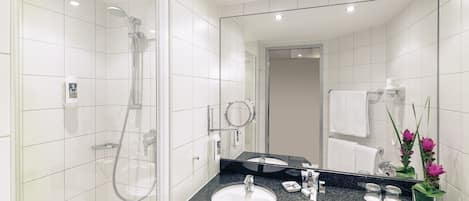 A modern bathroom with a glass-enclosed shower, a sink with a black countertop, and a large mirror.