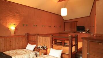 A cozy room with two beds, a wooden desk, a television, and a small kitchen area.