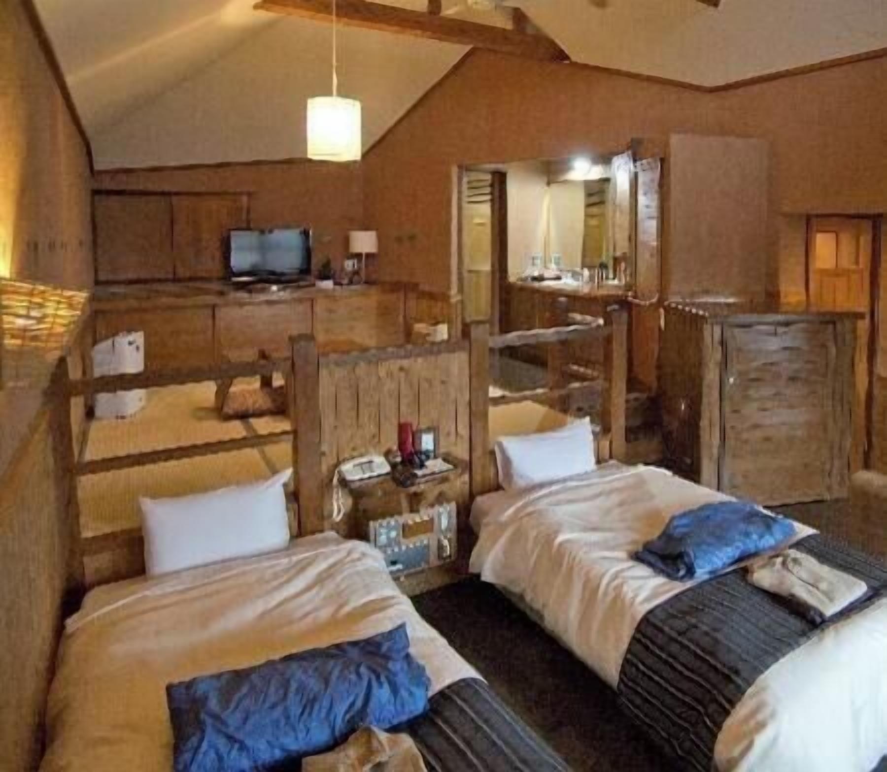 Ein rustikales Zimmer mit zwei Betten, einem Fernseher, einem Spiegel und Holzmöbeln.