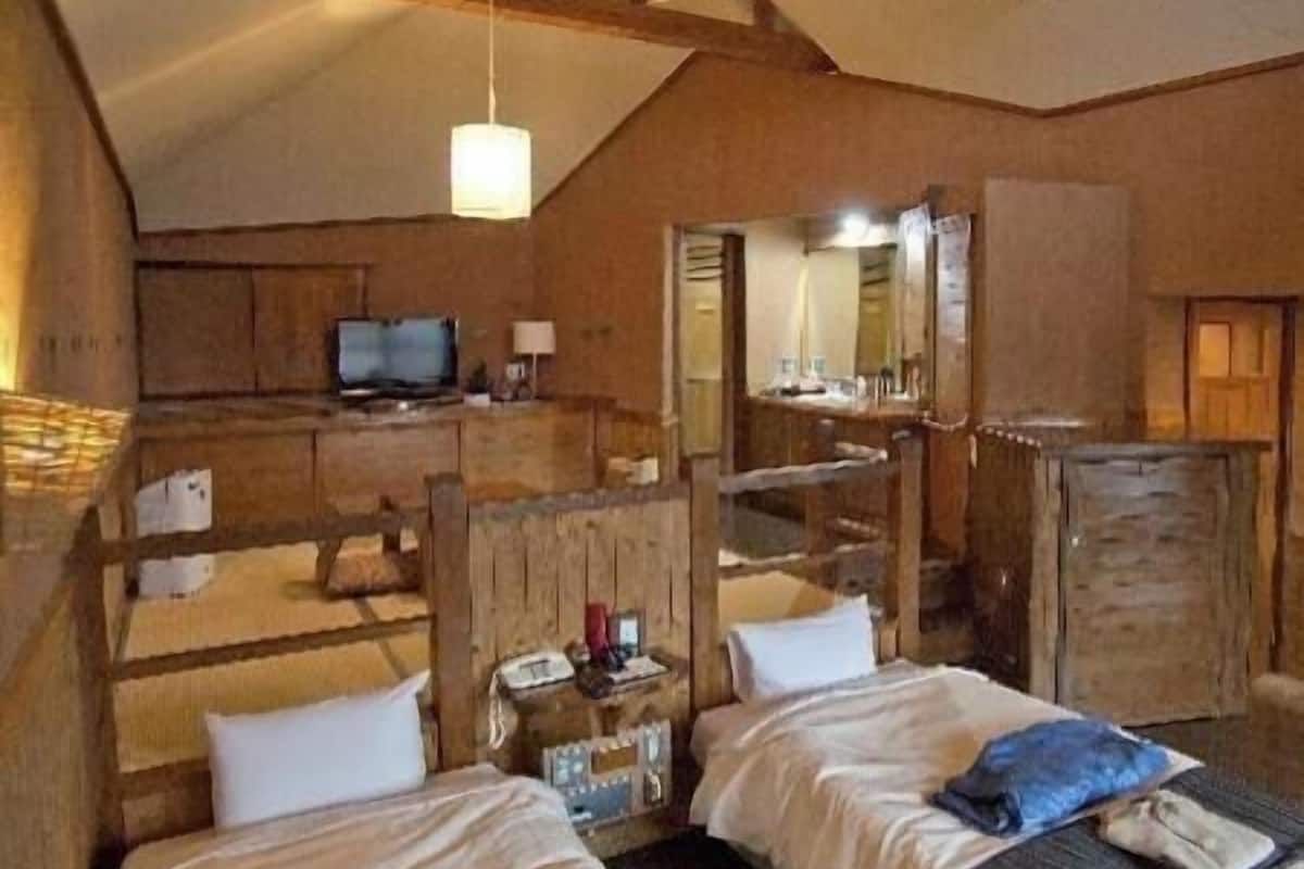 A rustic room with two beds, a television, a mirror, and wooden furniture.