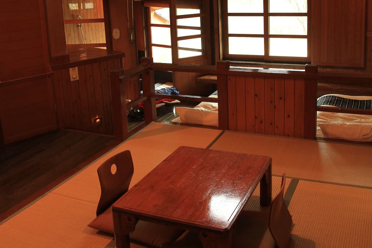 A traditional Japanese-style room with tatami flooring, a wooden table, and a hanging lamp.